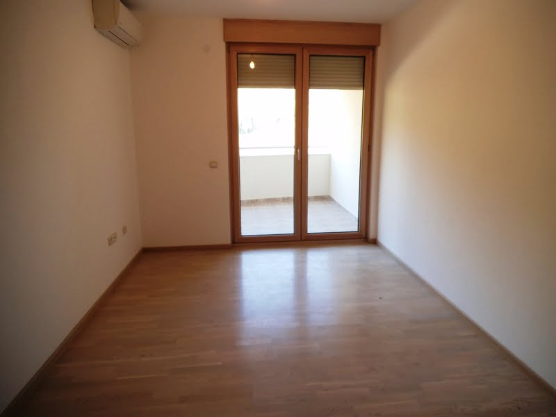 Bright living room with parquet flooring and access to the balcony in an apartment, Bečići, Montenegro.