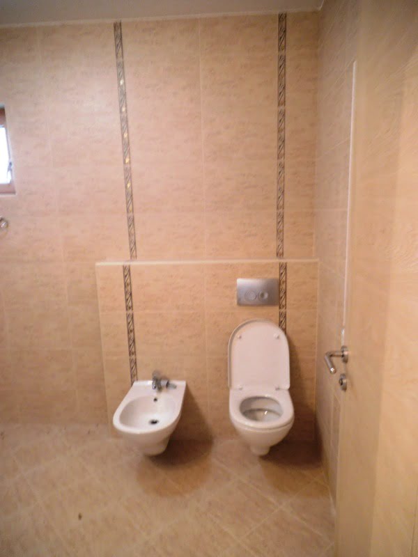 Bathroom with wall-mounted toilet and bidet in an apartment, Bečići, Montenegro. Light-colored tiles, modern interior.