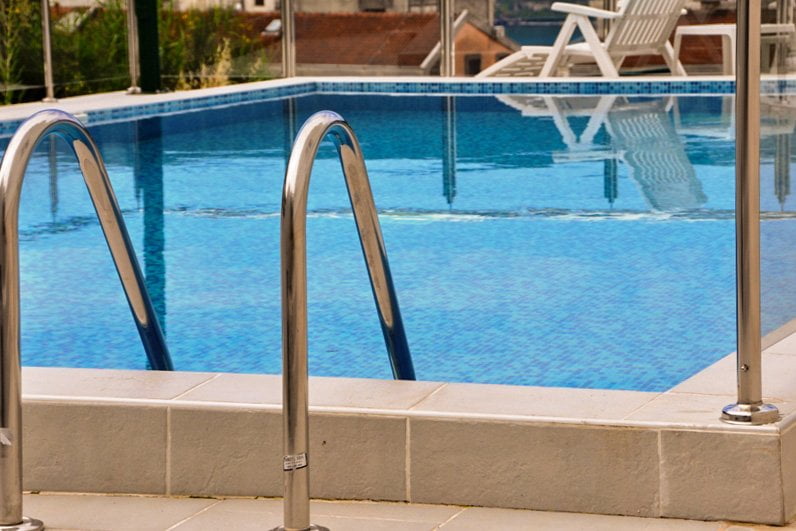 An outdoor swimming pool with blue tiles and sun loungers on the terrace of an apartment in Herceg Novi, Montenegro.