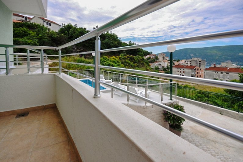 Balcony with a view of the sea and pool in an apartment, Herceg Novi, Montenegro: modern railing and tiled floor.