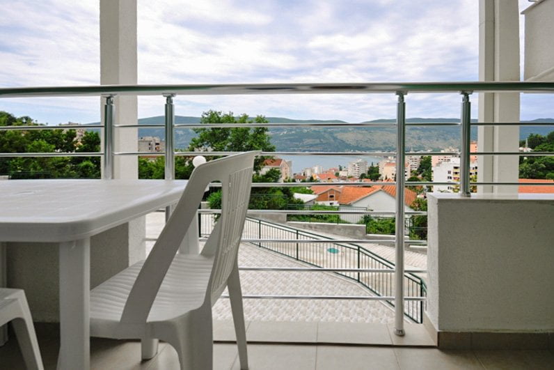 Balcony with plastic furniture and a view of the sea and the city of Herceg Novi, Montenegro. Apartment No. 758 with a panoramic view.