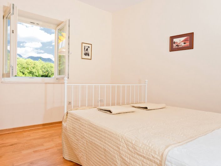 Bright bedroom with a white bed and a view of the mountains in an apartment, Herceg Novi, Montenegro.