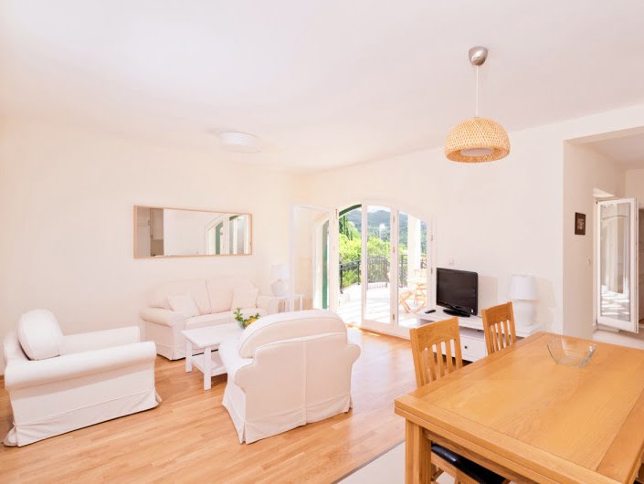 Bright living room with white furniture and a dining area in an apartment in Herceg Novi, Montenegro, with access to the terrace.