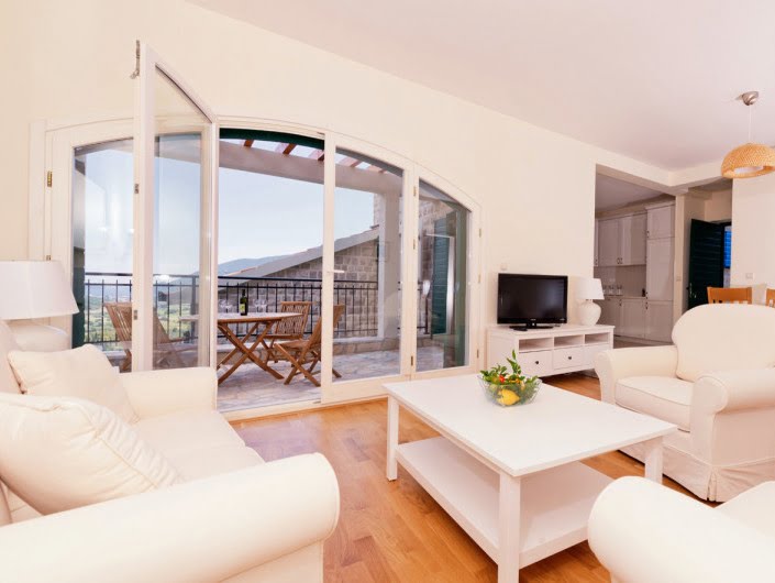 Bright living room with white furniture and access to the terrace in an apartment in Herceg Novi, Montenegro.