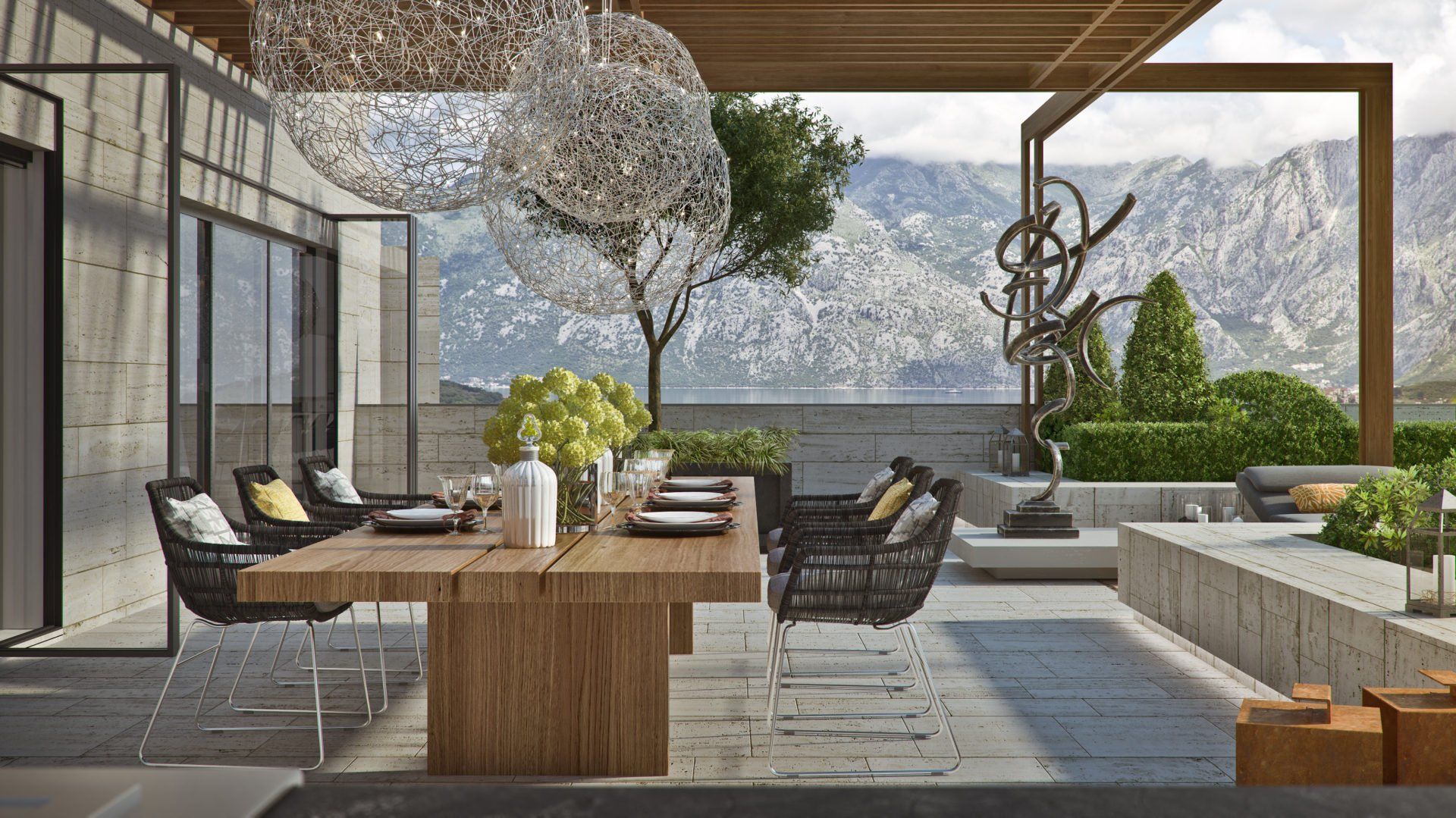Terrace of a luxury residential complex in Kotor, Montenegro: dining area with a wooden table, designer lights, and mountain views.