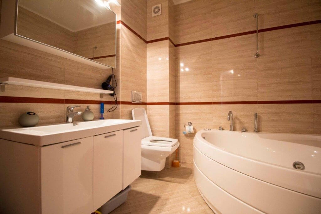Modern bathroom with a corner bathtub and white furniture in an apartment, Stoliv, Bay of Kotor, Montenegro.