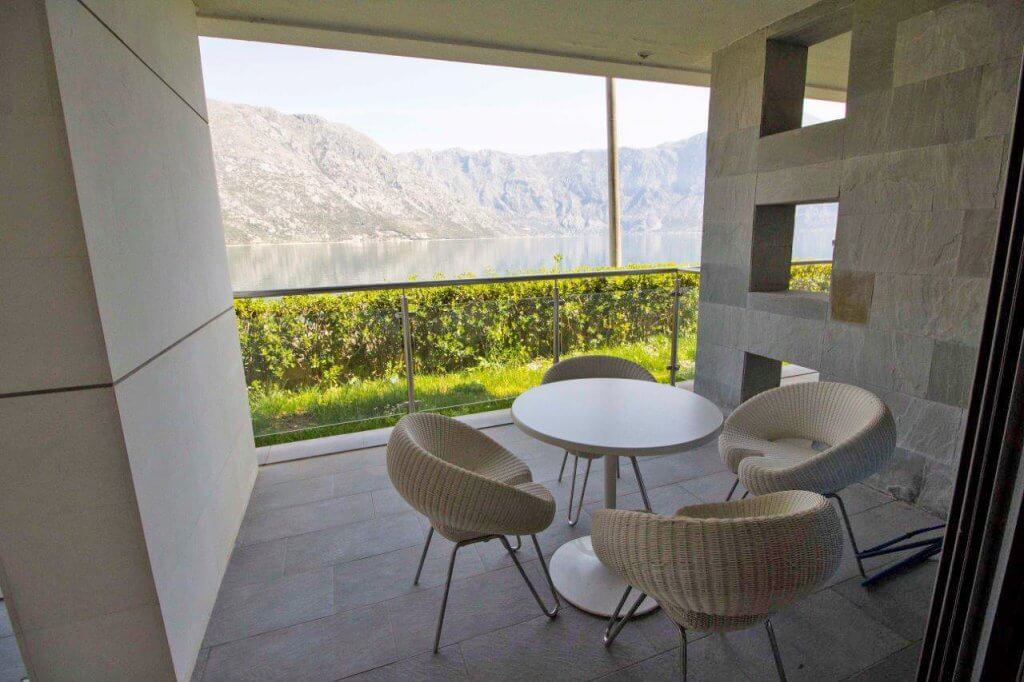 Terrace with wicker furniture and a view of the Bay of Kotor, Stoliv, Montenegro. Modern stone finish.