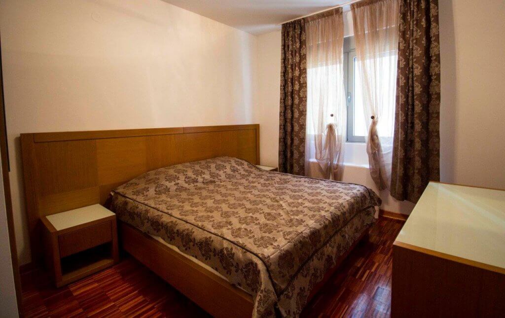 Cozy bedroom with a double bed in an apartment in Stoliv, Bay of Kotor, Montenegro. Parquet flooring and decor.