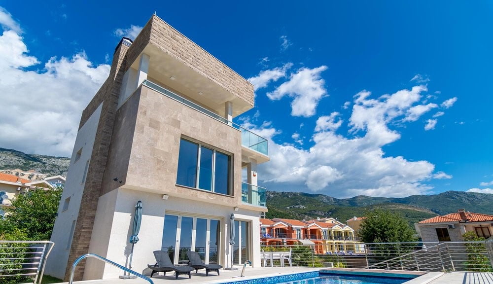 Modern villa with a swimming pool and terraces in Becici, Montenegro: view of the building facade and mountain landscape.