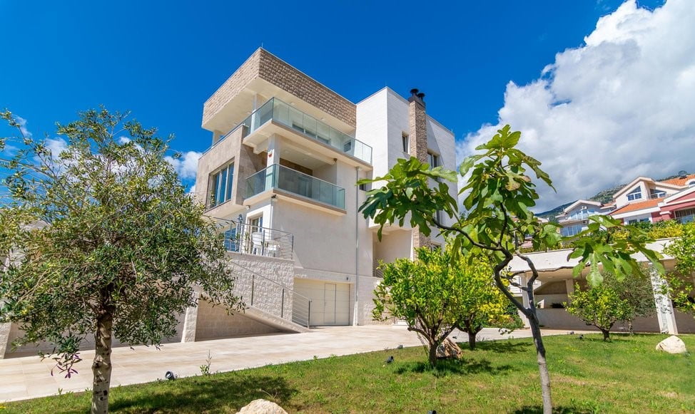 Modern three-story villa with terraces and a garden in Bečići, Montenegro: view of the house facade and the surrounding area.