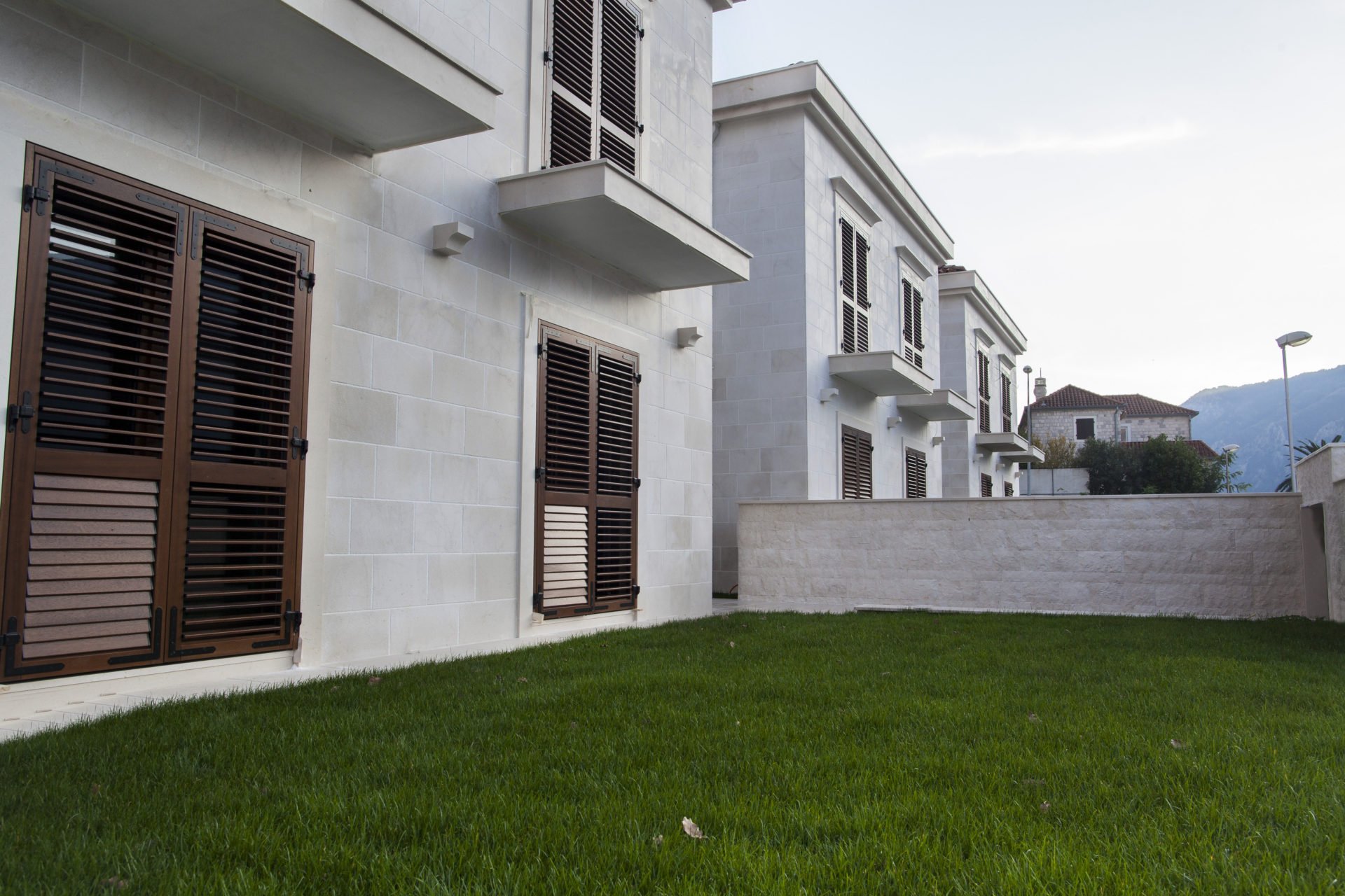 Modern villa with a stone facade and green lawn in a residential complex, Dobrota, Montenegro.