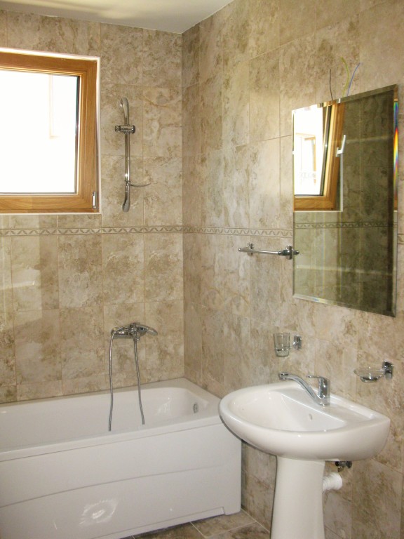 Bathroom with white sanitary ware and stone-look tile finishes in a residential complex, Igalo, Montenegro.