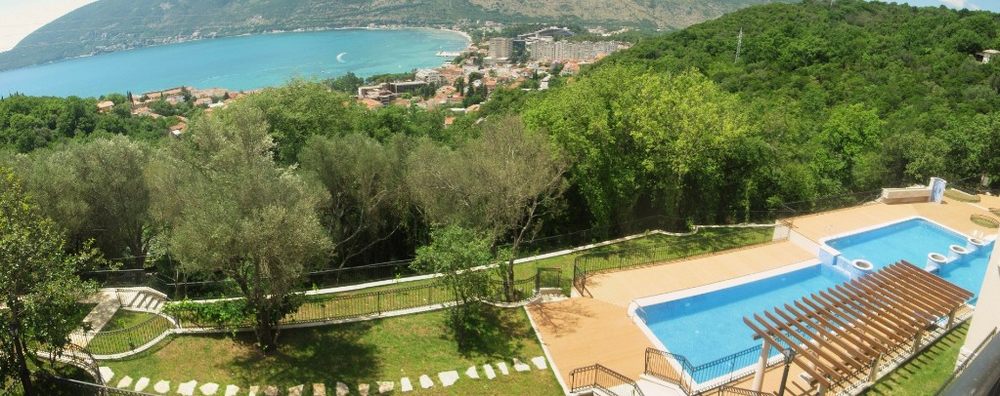 View of the outdoor pool and panoramic bay in Igalo, Herceg Novi, Montenegro: terrace with pergola and green garden.