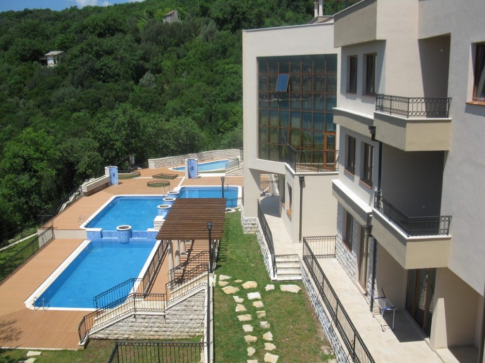 Residential complex in Igalo, Montenegro: modern apartments with cascading pools and views of a lush forested area.