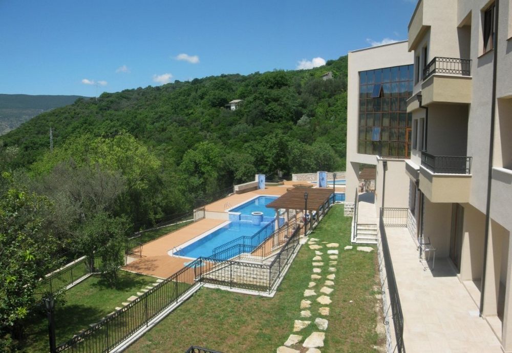 Residential complex in Igalo, Montenegro: a modern building with a swimming pool, landscaped grounds, and panoramic mountain views.