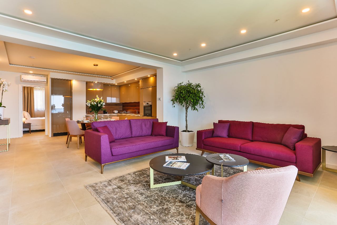 Modern living room with purple sofas in a residential complex in Rafailovici, Montenegro: stylish interior and kitchen-dining area.