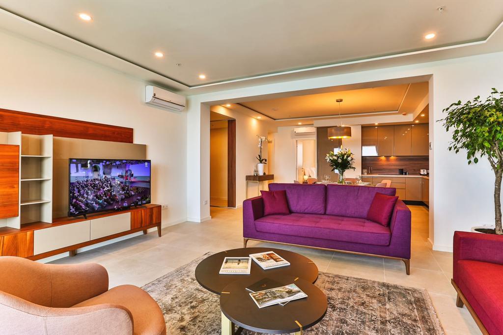 Modern living room with a purple sofa and kitchen in a beachfront residential complex in Rafailovici, Montenegro.