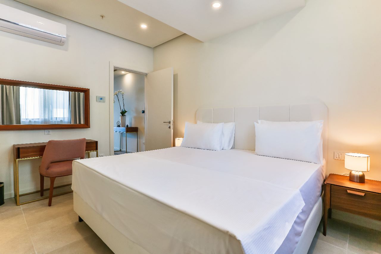 Modern bedroom with a double bed and a vanity table in a beachfront residential complex, Rafailovici, Montenegro.