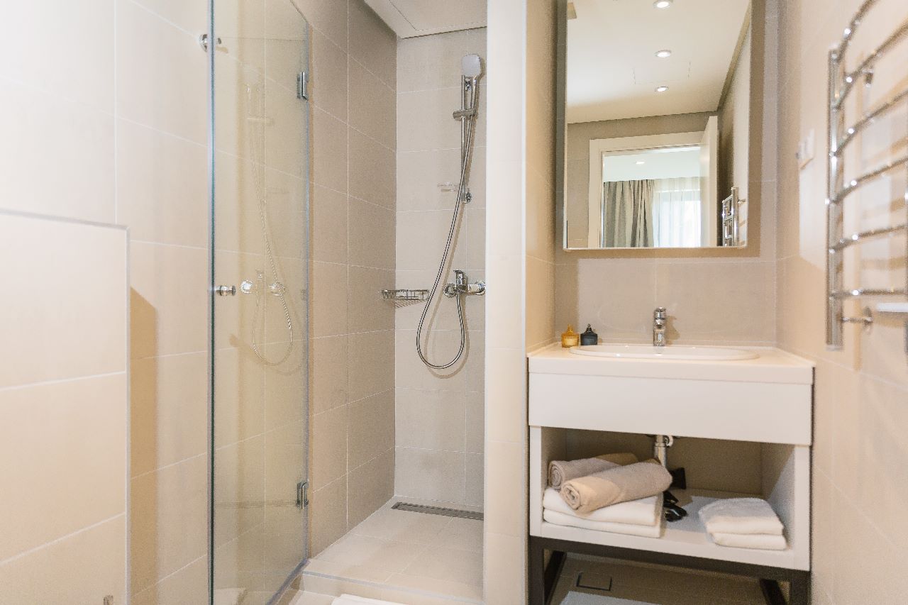 Modern bathroom with a walk-in shower in a residential complex in Rafailovici, Montenegro: light-colored tiles and stylish fixtures.