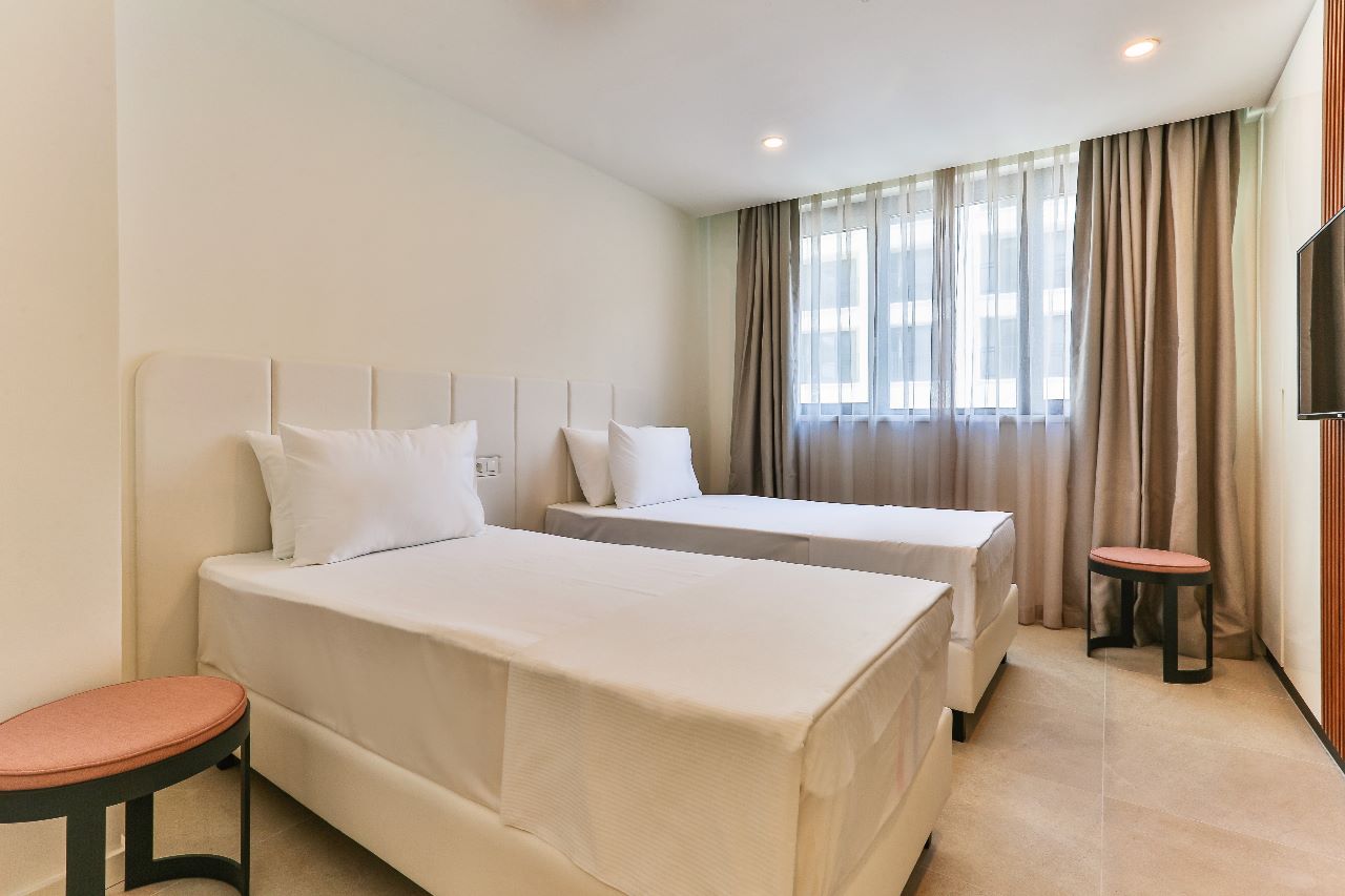 Modern twin bedroom in a residential complex in Rafailovici, Montenegro: bright interior, panoramic window, TV.