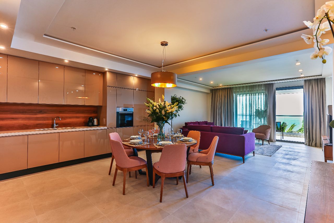 Modern living room with a kitchen in a residential complex in Rafailovici, Montenegro: dining area, purple sofa, and sea view.