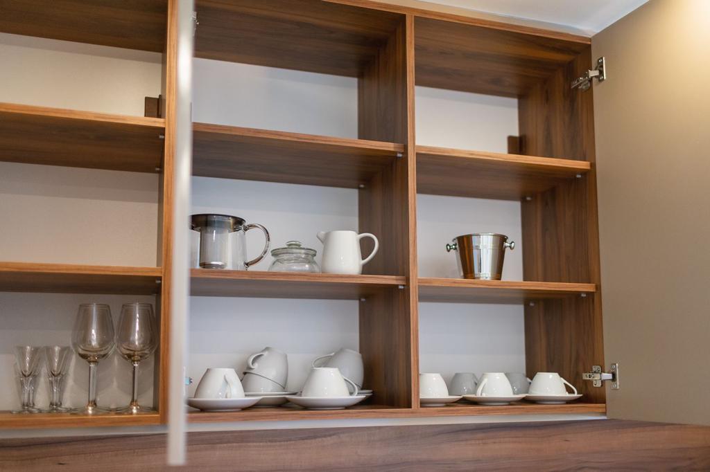 Open kitchen shelving with tableware in a modern apartment, residential complex in Rafailovici, Montenegro, stylish kitchen interior.