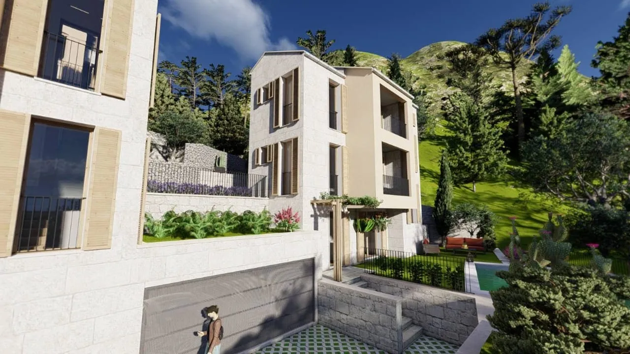 Exterior view of a multi-story stone building with balconies, garden, and pool set against a mountain backdrop.