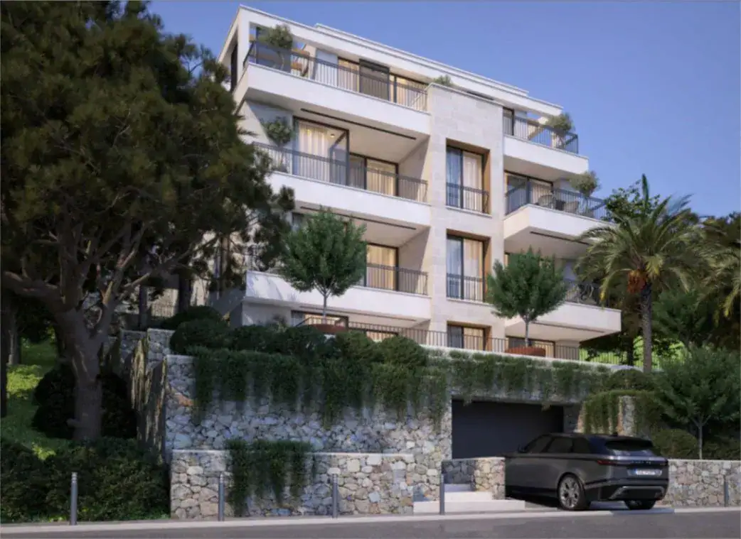 Modern residential complex in Tivat, Montenegro: building facade with terraces, stone cladding, and parking by the house.