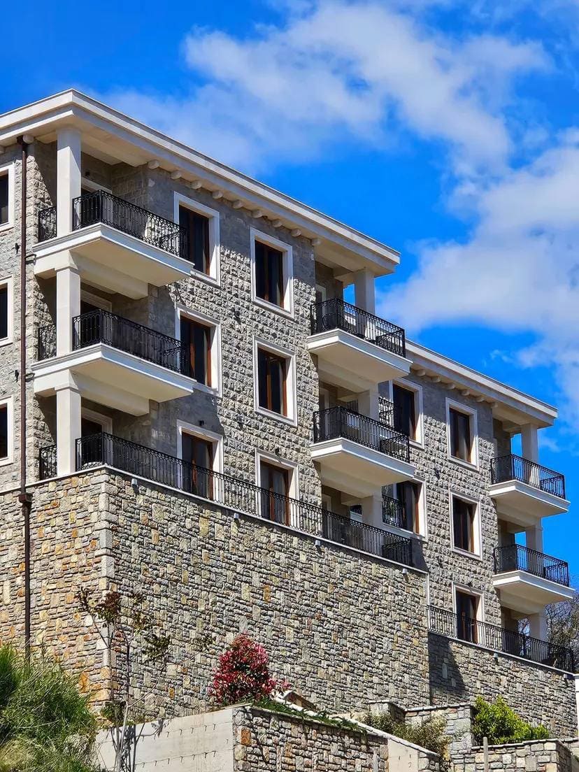 Facade of a modern residential building made of natural stone with balconies in Budva, Montenegro.