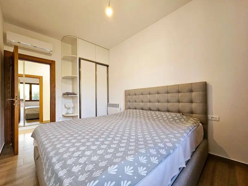 Cozy bedroom with a double bed and built-in wardrobe in an apartment for sale, Budva, Montenegro.