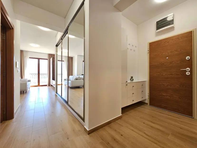 Hallway with a mirrored sliding wardrobe and an entrance door in a modern apartment in Budva, Montenegro.