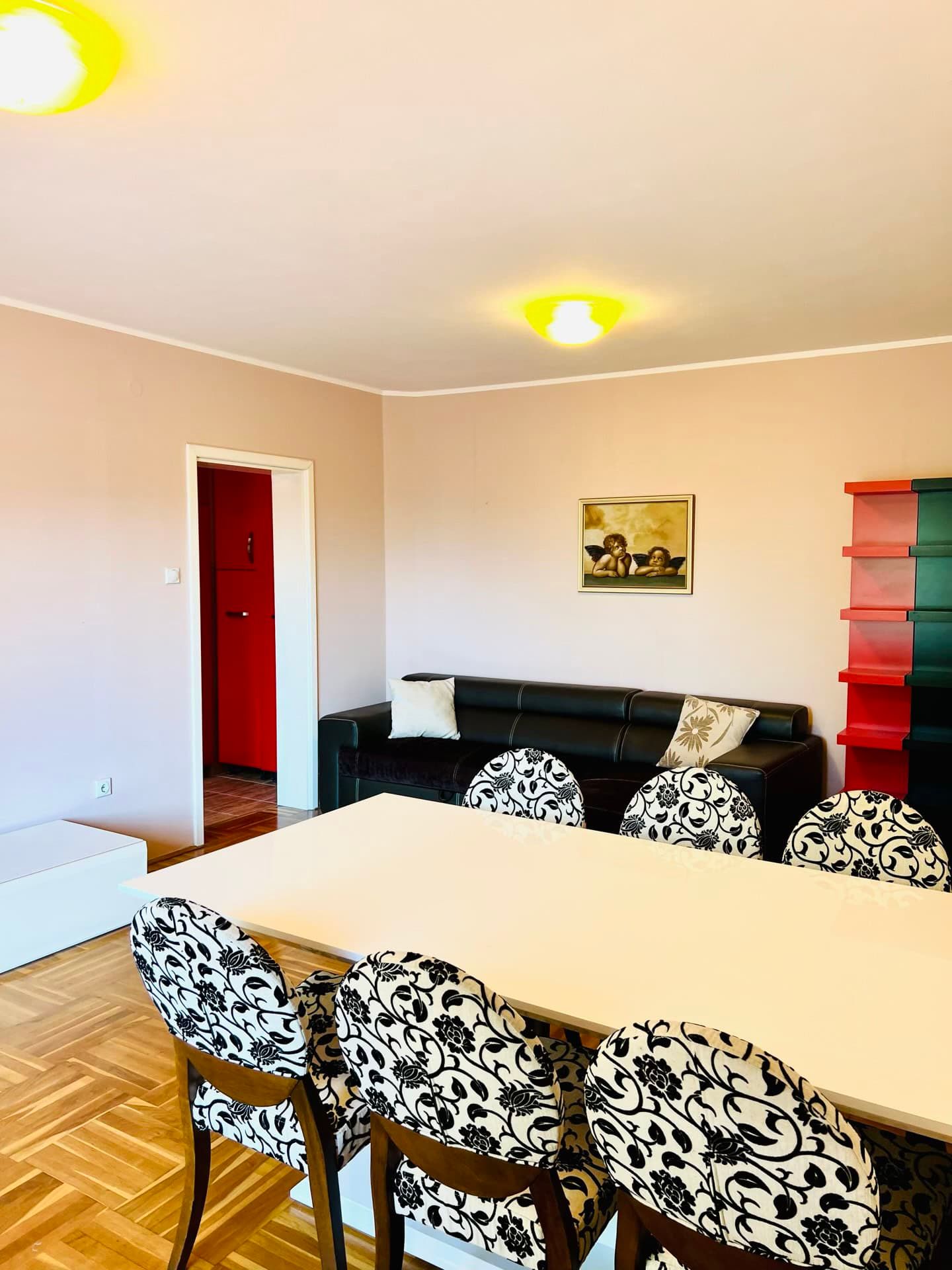 Living room with dining area in an apartment in Petrovac, Montenegro: black sofa, table and chairs with patterned upholstery.