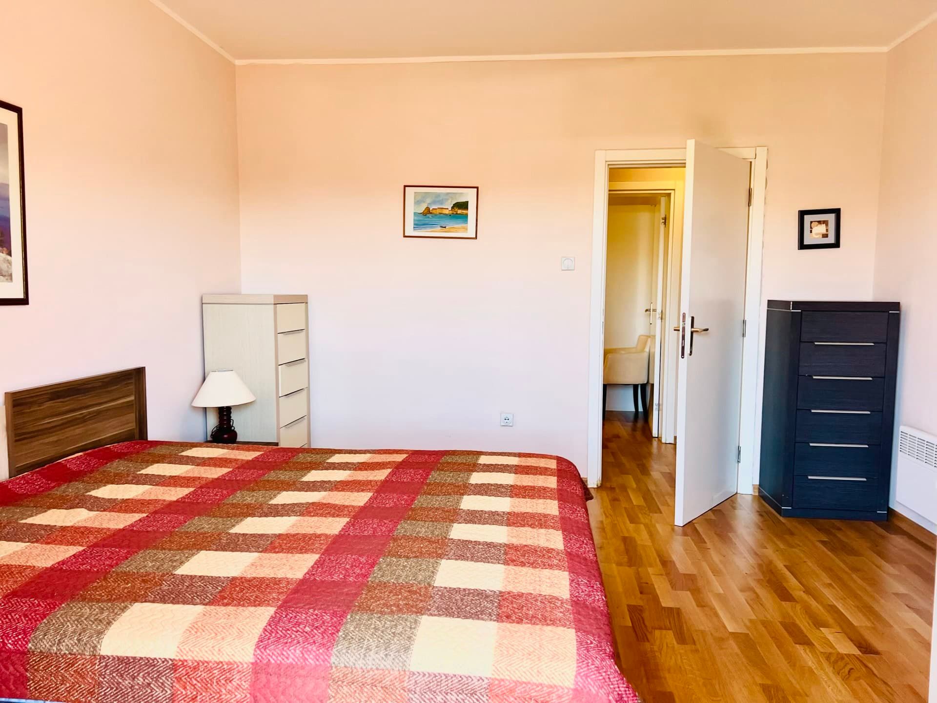 Bright bedroom with a double bed and parquet flooring in an apartment in Petrovac, Montenegro. Interior view with dressers.