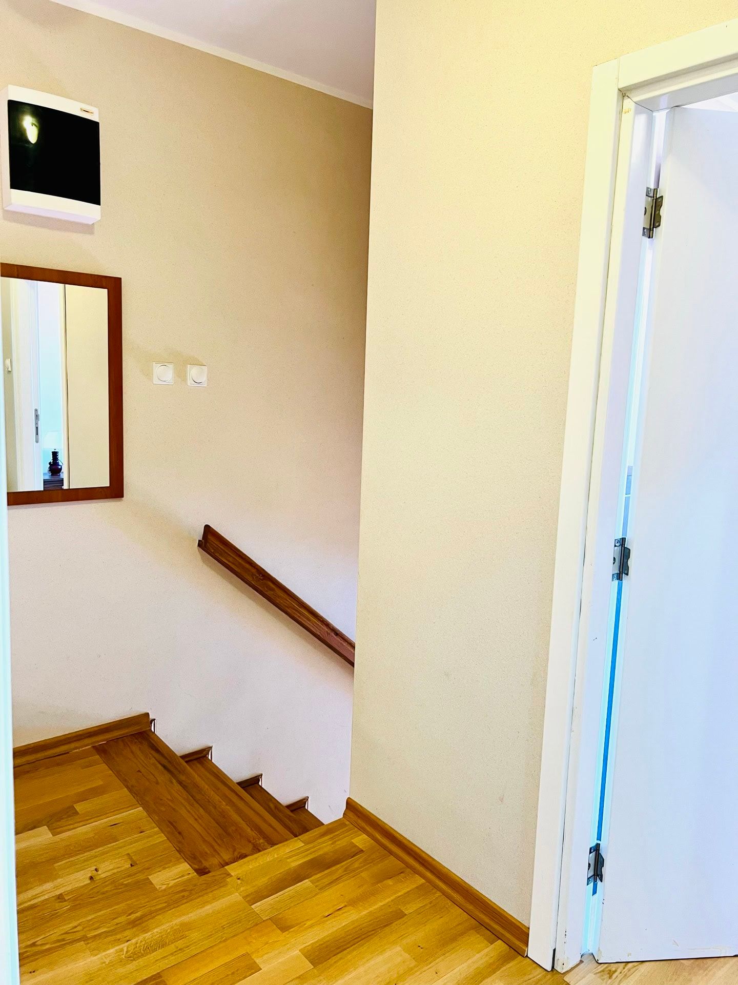 Bright staircase interior in a duplex, Petrovac, Montenegro: wooden steps, railing, and a wall mirror in the hallway.