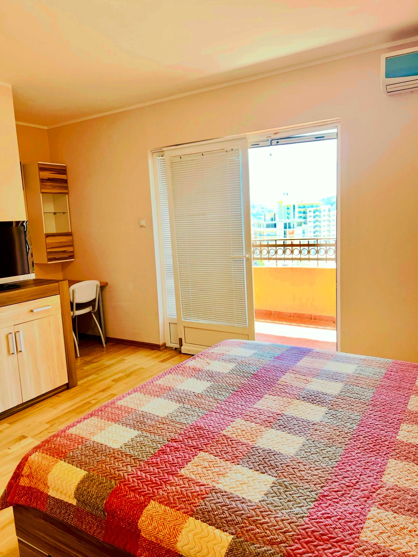Bedroom in an apartment in Petrovac, Montenegro: double bed, light-colored furniture, access to a balcony with city views.