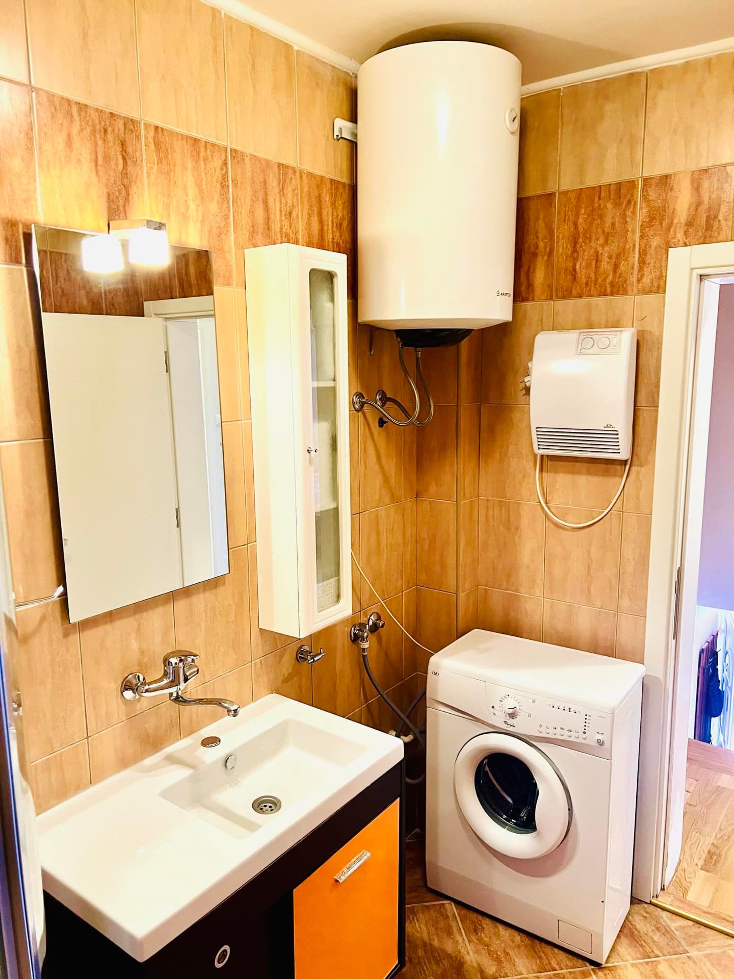 Bathroom in an apartment in Petrovac, Montenegro: sink with vanity, mirror, washing machine, and wall-mounted boiler.