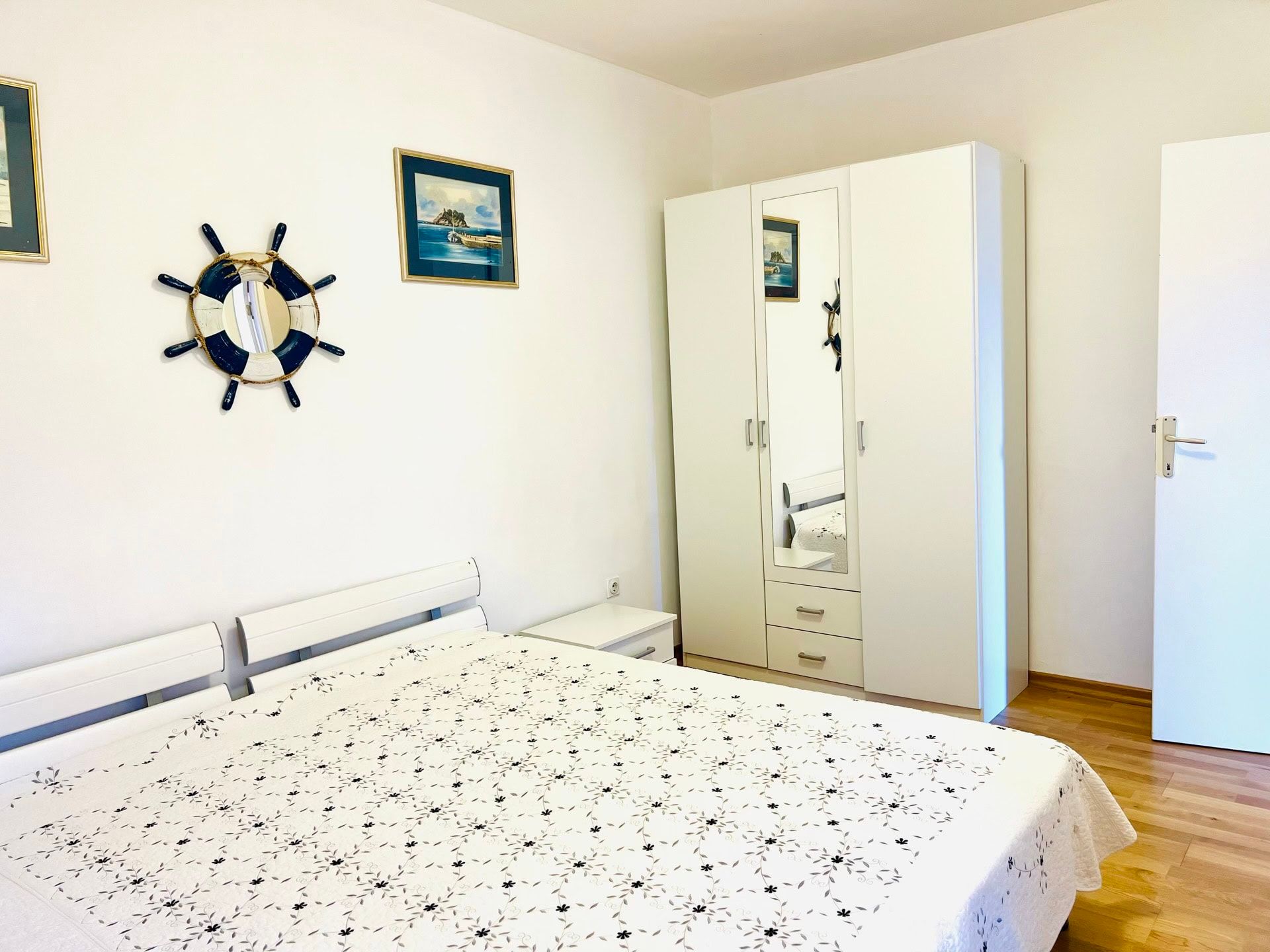 Bright bedroom with white furniture and nautical decor in an apartment in Petrovac, Montenegro.