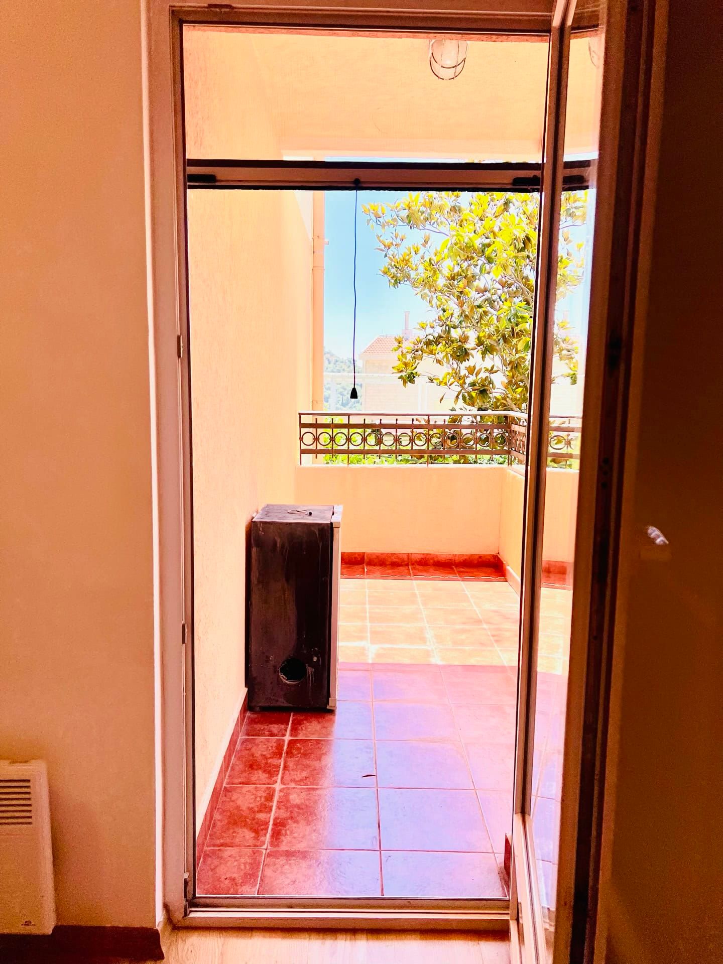 View from the room onto an open balcony with terracotta tiles in an apartment in Petrovac, Montenegro.