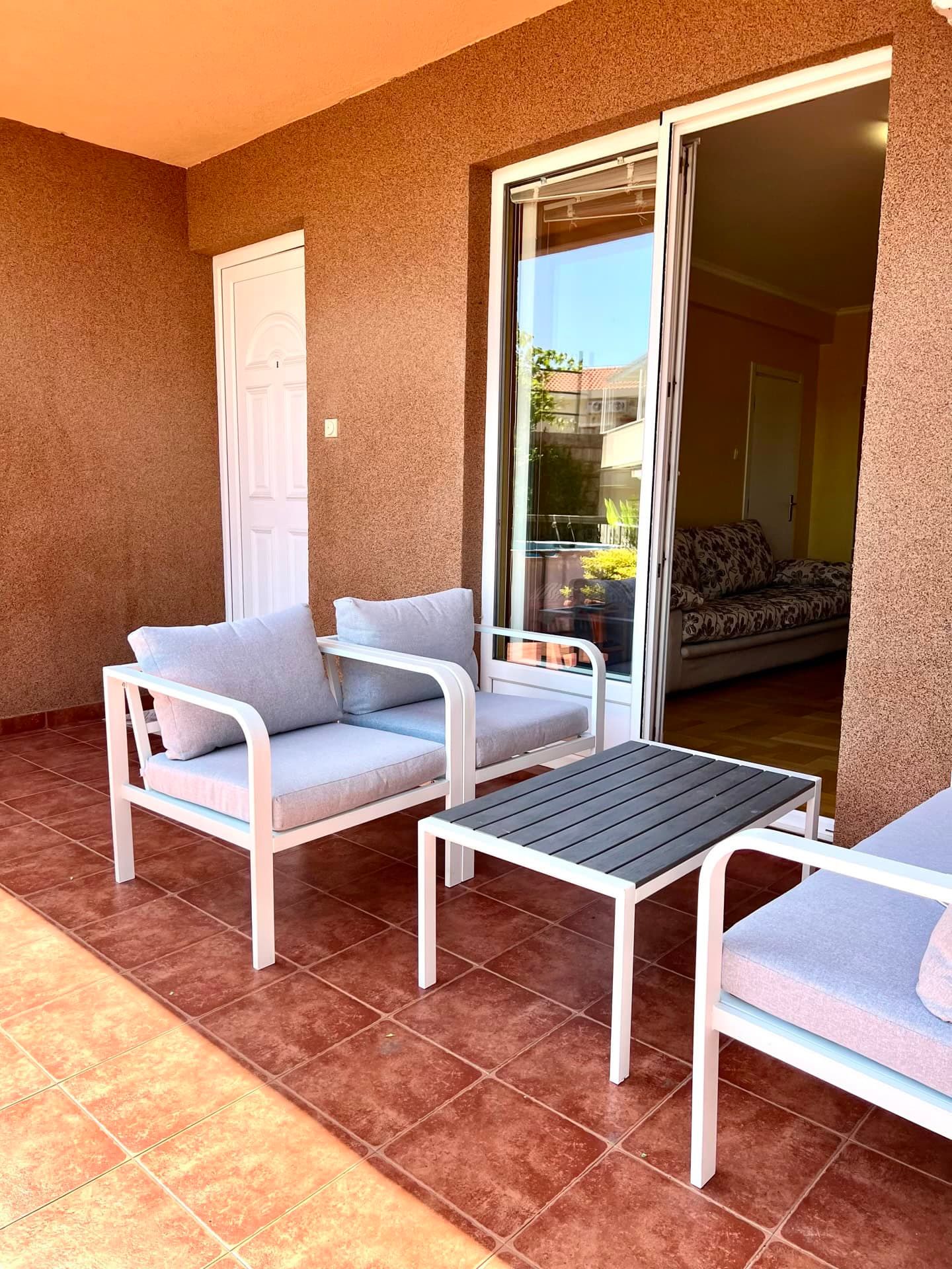 Cozy terrace with garden furniture in an apartment in Petrovac, Montenegro: view of the balcony with access to the living room.