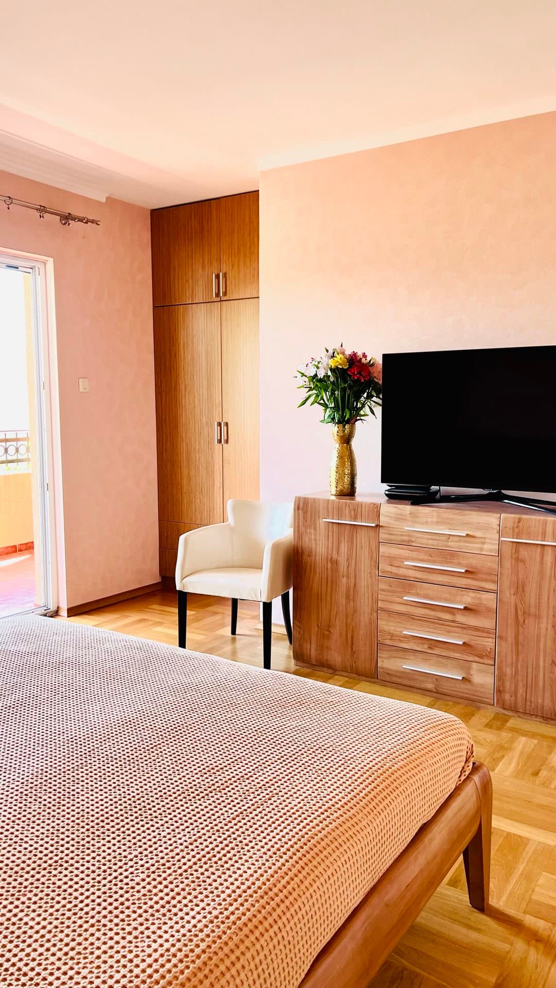 Cozy bedroom with wooden furniture, parquet flooring, and access to the balcony in an apartment in Petrovac, Montenegro.