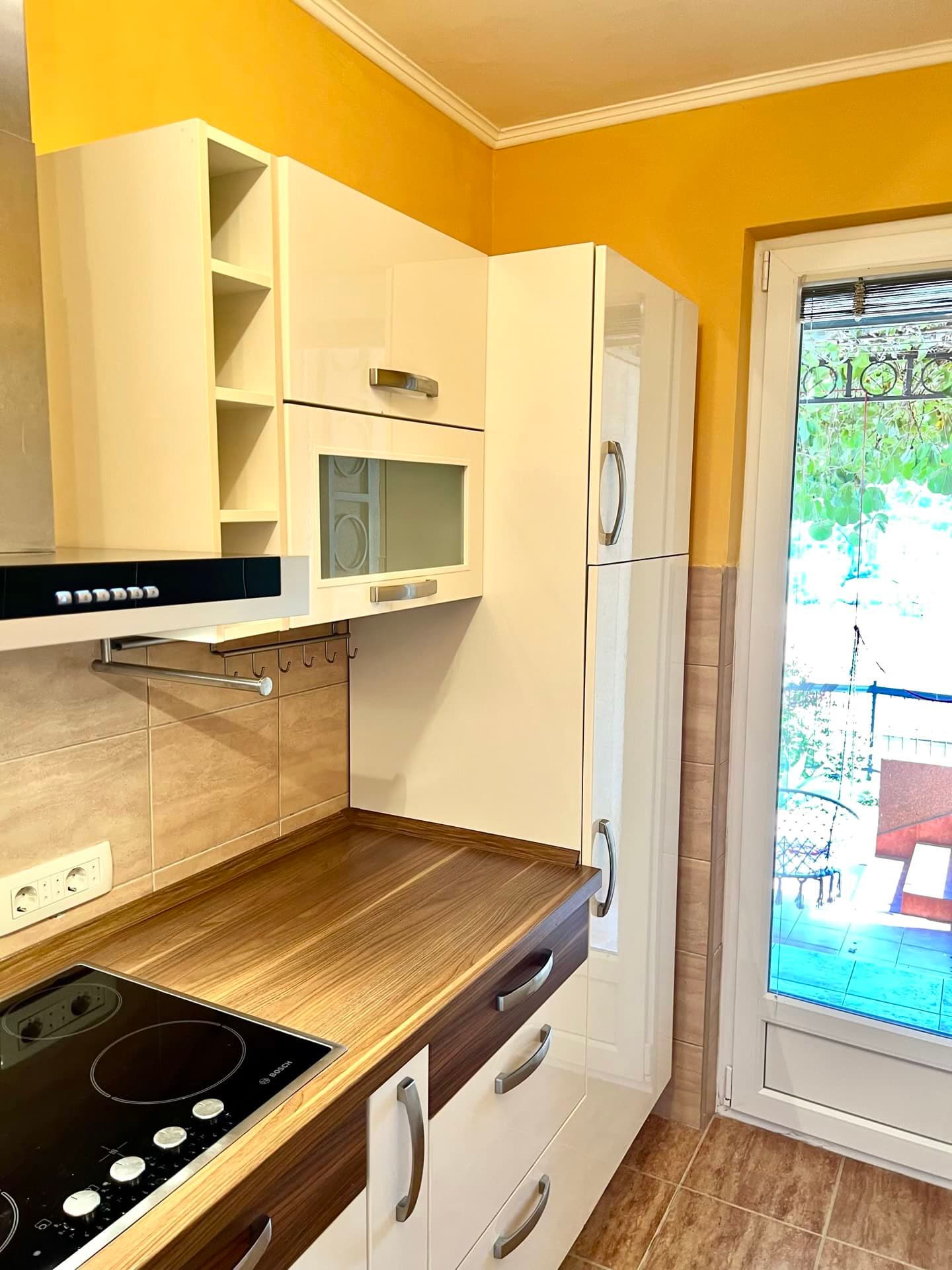Modern kitchen with white cabinetry and access to the terrace in an apartment, Petrovac, Montenegro.