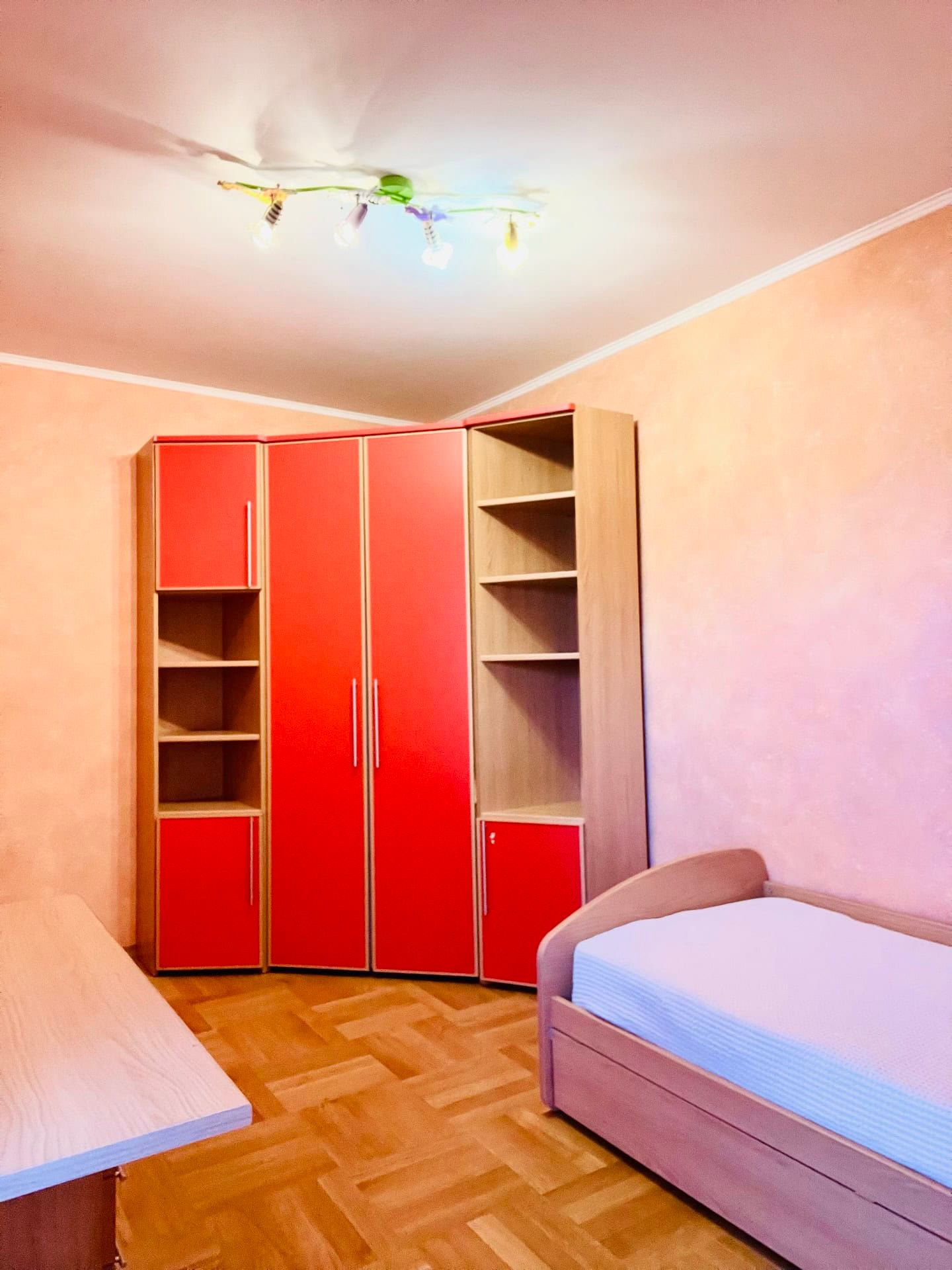 Children's bedroom with a red wardrobe and bed in an apartment in Petrovac, Montenegro. Bright interior with parquet flooring.