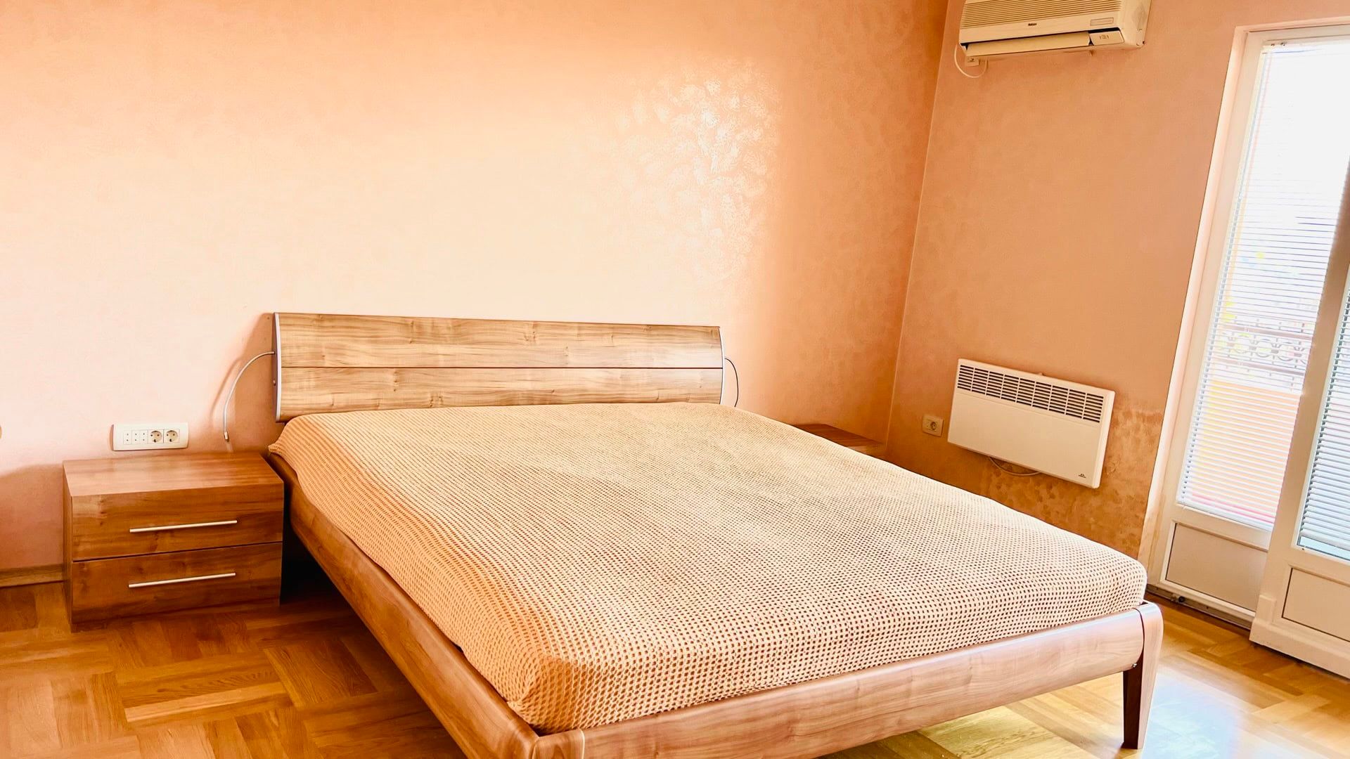 Bedroom with a double bed and parquet flooring in an apartment in Petrovac, Montenegro. Cozy interior with air conditioning.