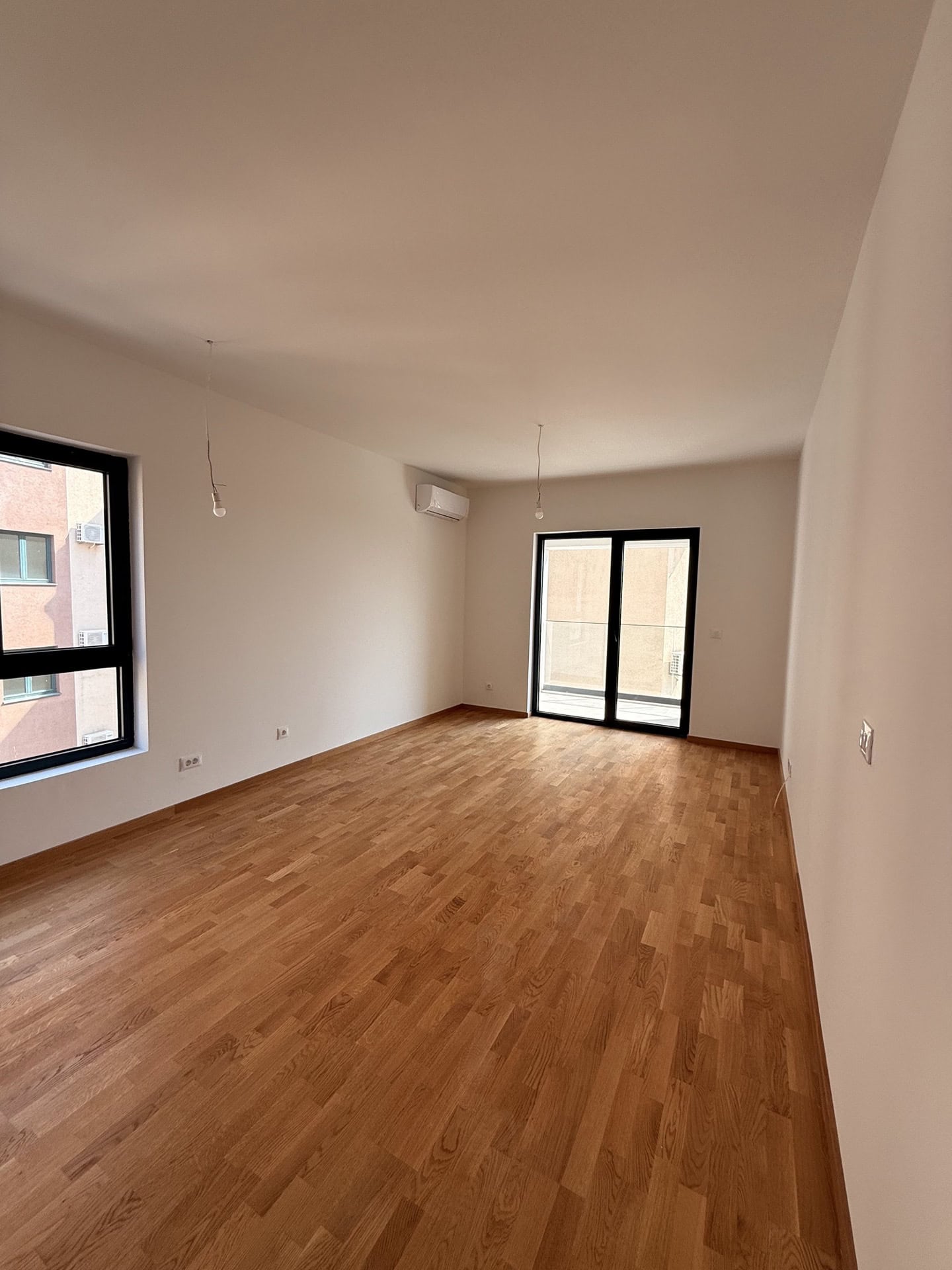 Bright living room with parquet flooring and access to the balcony in a new apartment, Becici, Montenegro.
