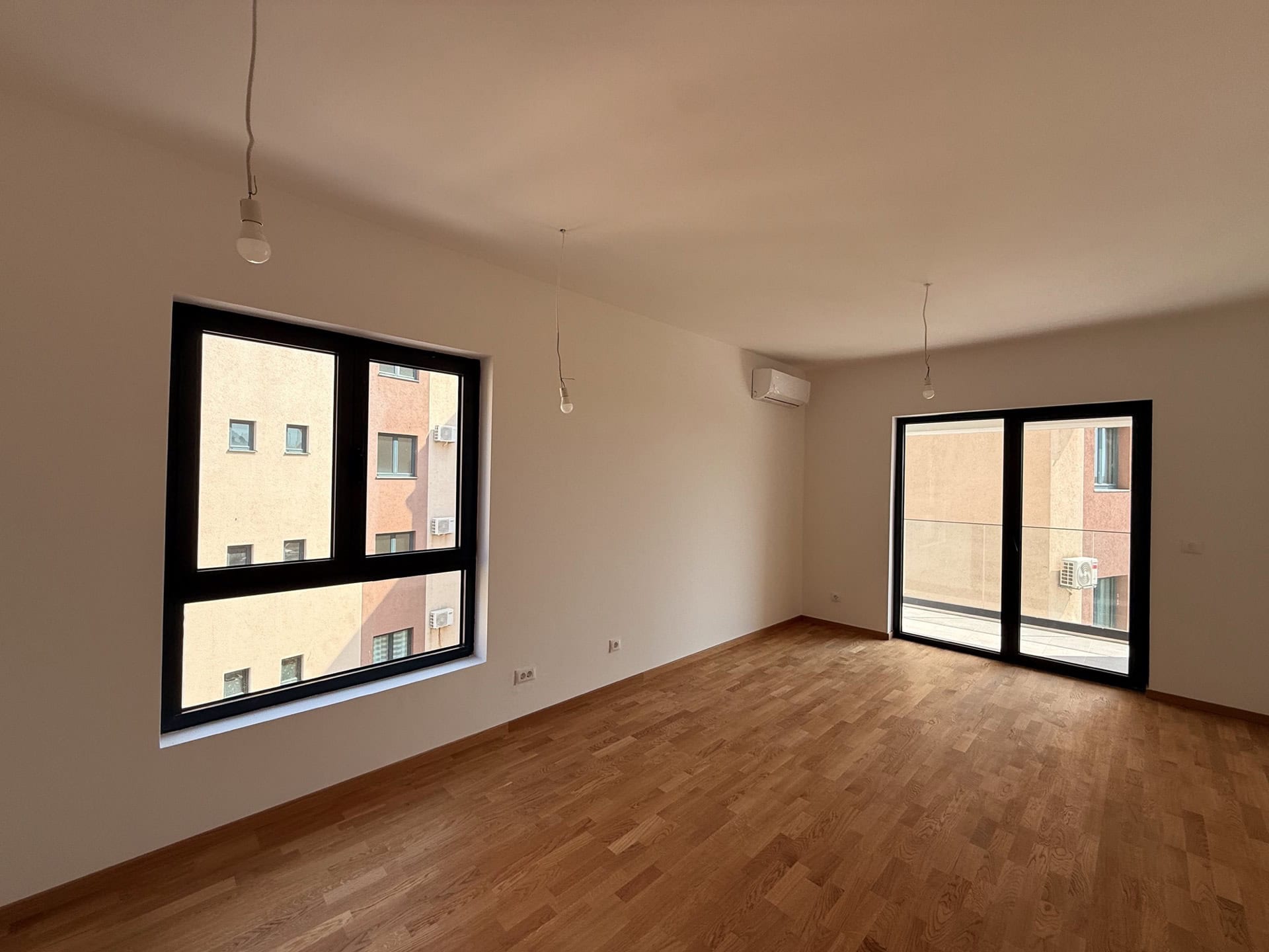 Bright living room with parquet flooring and panoramic windows in a new apartment, Becici, Montenegro.