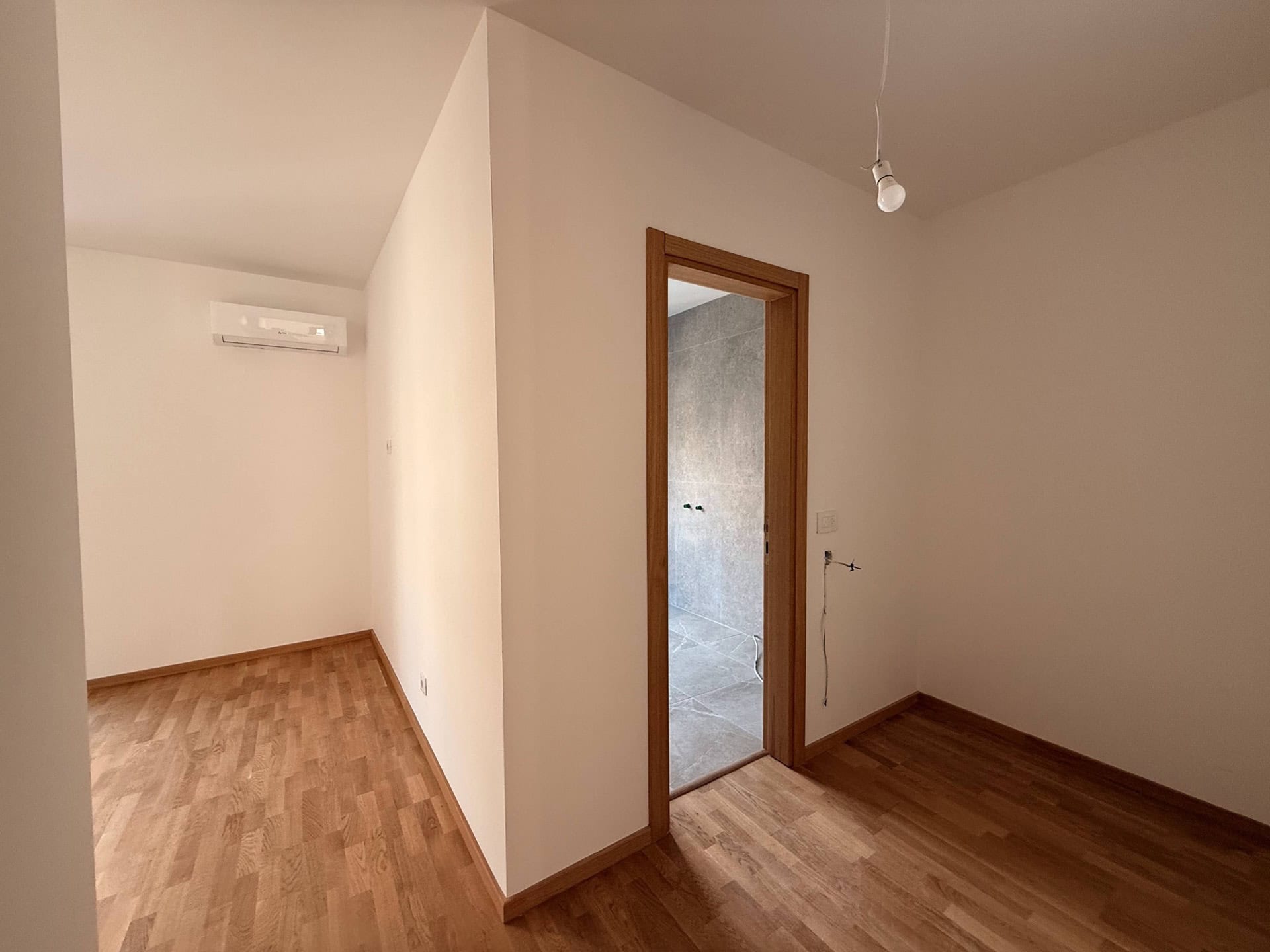 Bright living room with parquet flooring and air conditioning in the apartment, Becici, Montenegro, view of the bathroom finish.