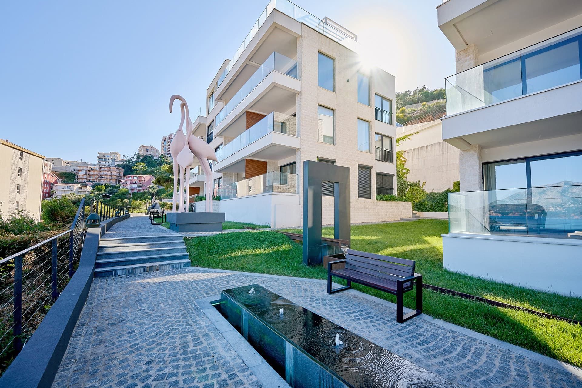 Modern residential complex with a fountain and flamingo sculpture in Budva, Montenegro: view of the landscaped grounds.