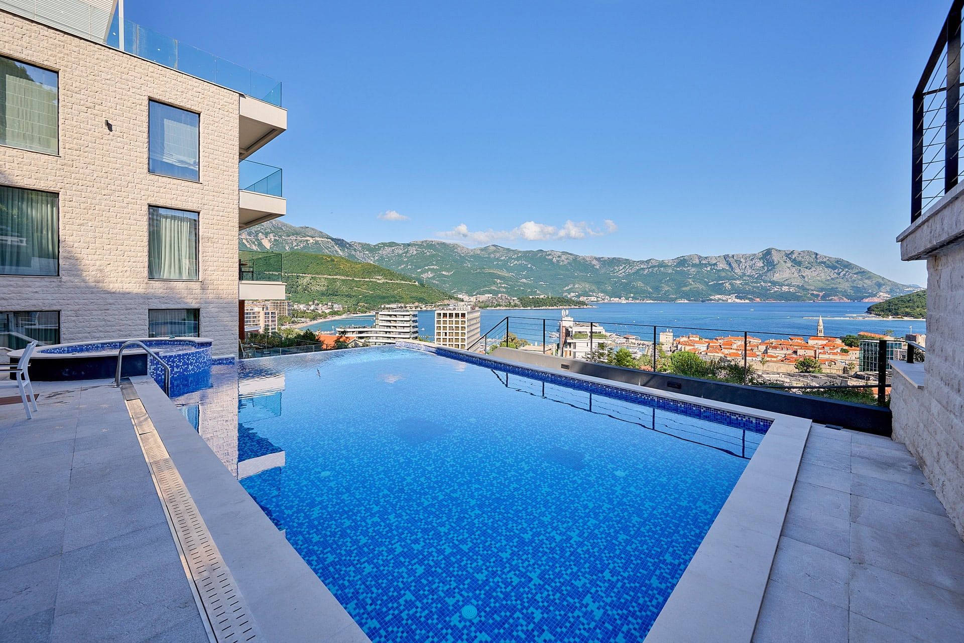 Infinity pool on the terrace of a luxury residential complex in Budva, Montenegro, with panoramic sea and mountain views.