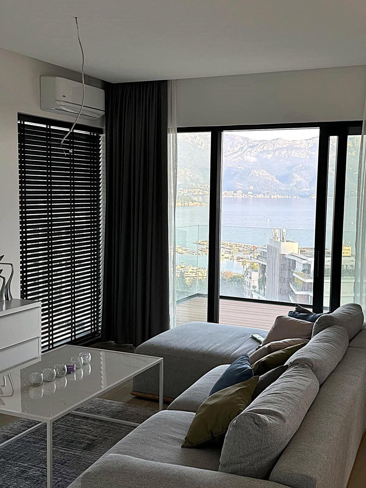 Living room in an apartment in Budva, Montenegro: panoramic sea and mountain views, modern furniture, and a stylish interior.