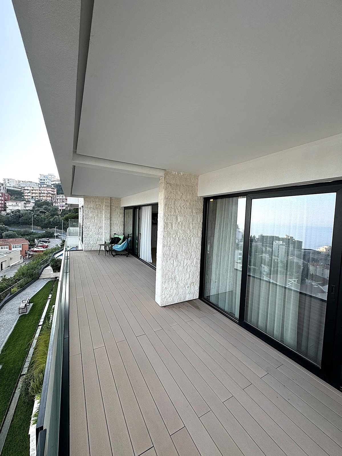 Spacious terrace with panoramic views in an apartment in Budva, Montenegro: decking, stone finishes, and glazing.